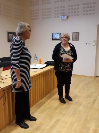 Puheenjohtaja Helka Urponen luovuttaa Suomen Lottaperinneliiton ansiomerkin Tuula Karjalaiselle.